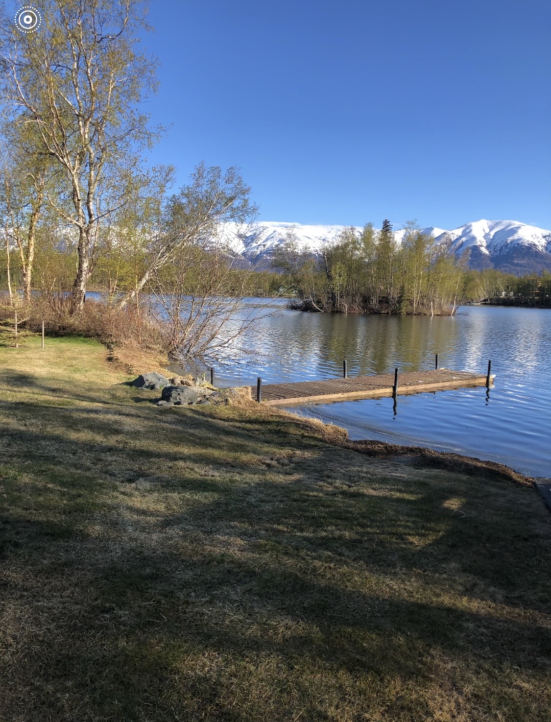 Waterfront property with dock on an Alaska lake, snow-capped mountains in background
