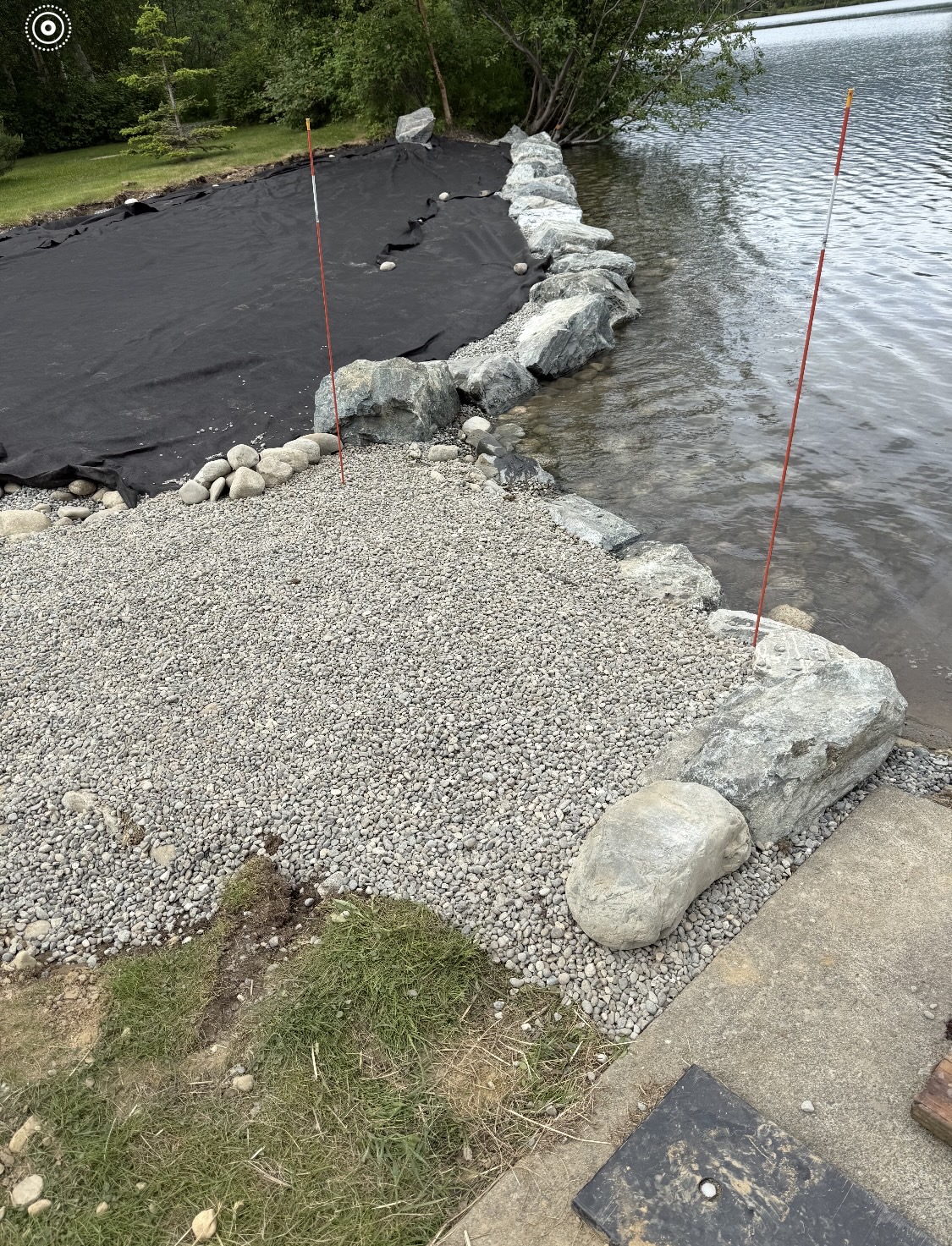 Close-up of riprap stone placement and geotextile fabric at the water's edge