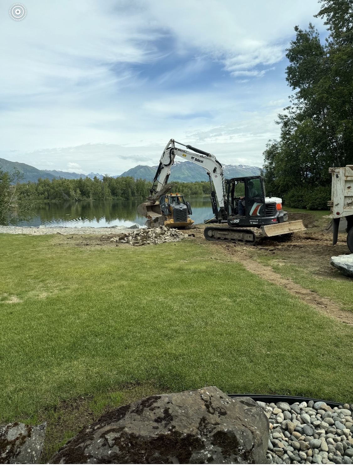 Bobcat excavator doing site grading and earthwork on a residential property near a lake in the Mat-Su Valley