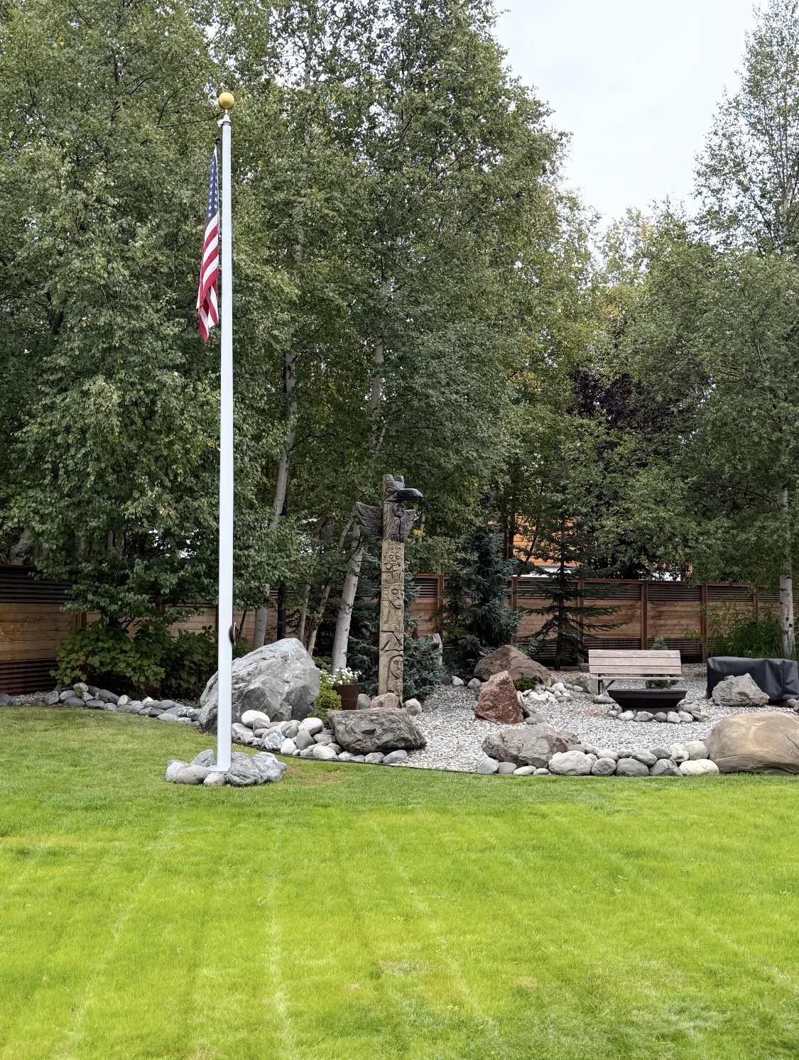 Finished residential yard with manicured lawn, flagpole, and boulder rock garden — Mat-Su Valley, Alaska