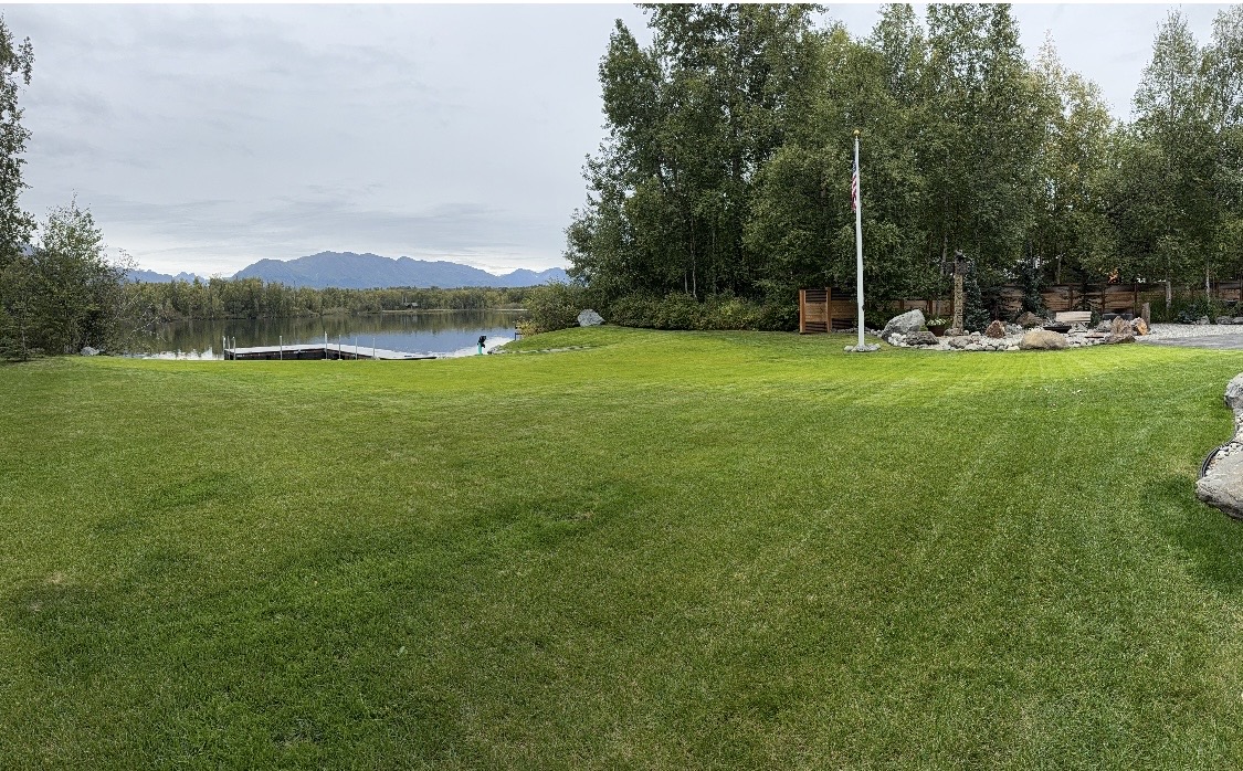 Completed residential waterfront property with lawn, dock, and riprap rock wall on an Alaska lake — Mat-Su Valley
